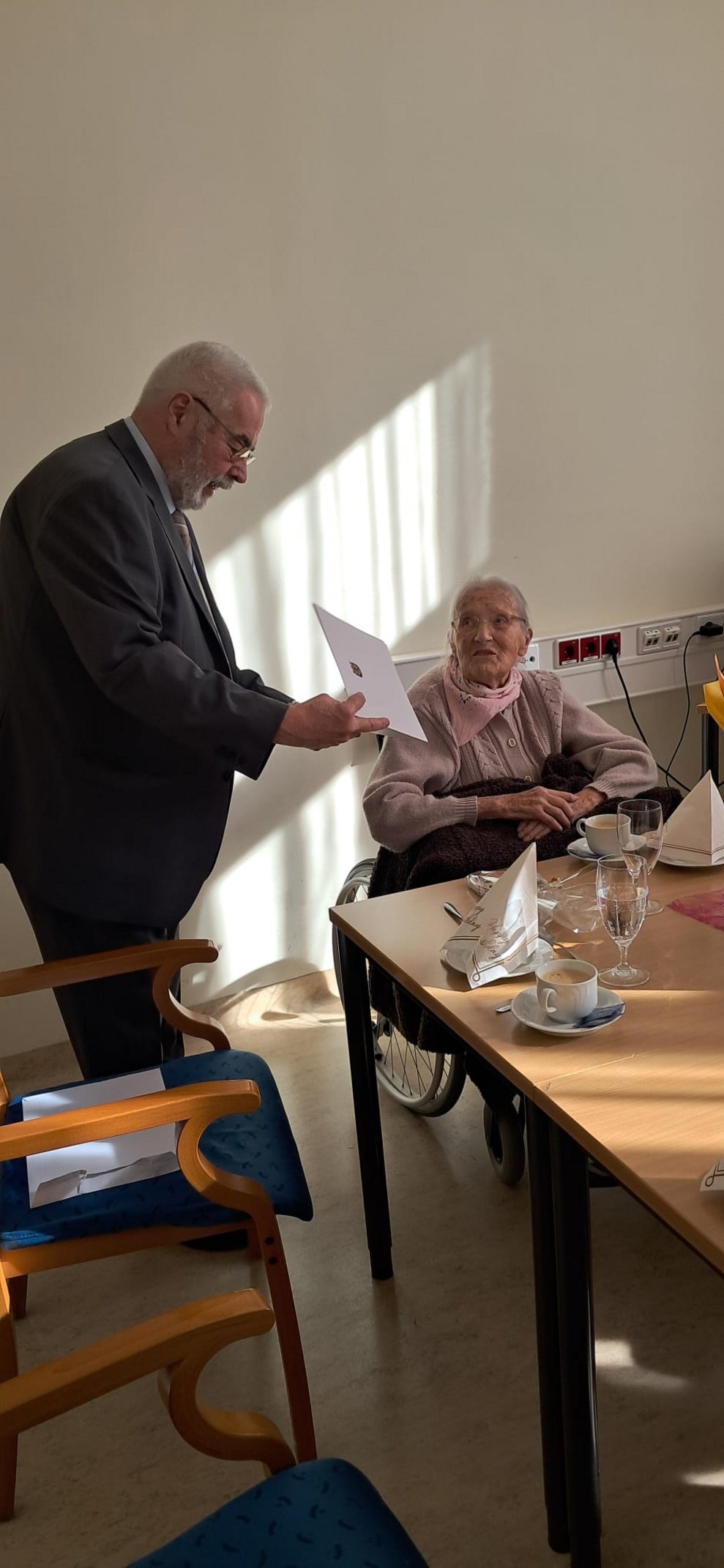 Mann und Bewohnerin. Mann hält Papierheft in den Händen.