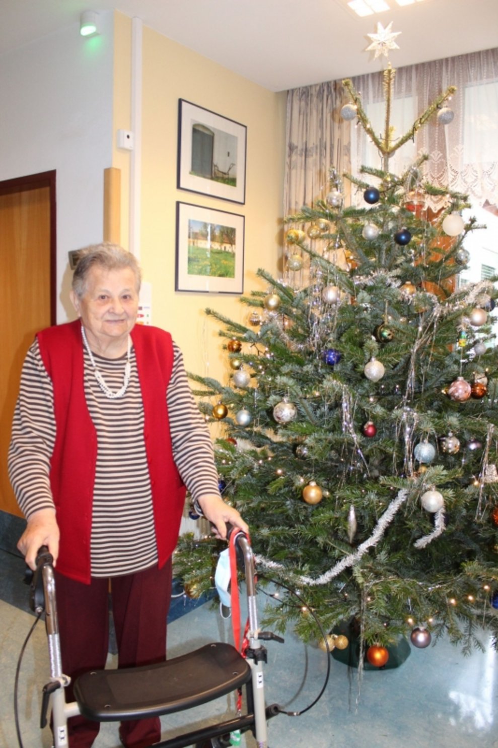 Eine Bewohnerin steht neben einem Christbaum.