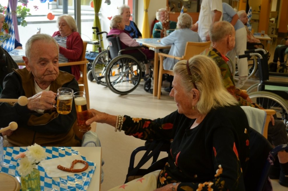 Ein Bewohner und eine Bewohnerin stoßen mit ihrem Bier an.