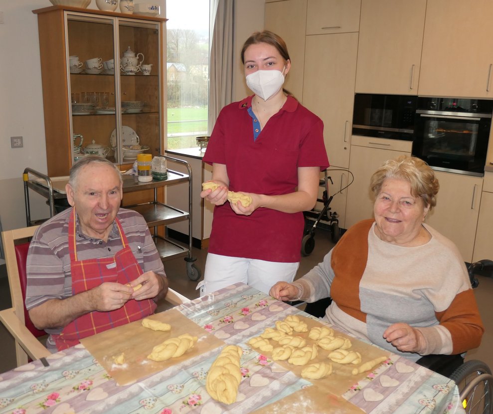Zwei Damen und ein Herr backen Osterkränze.