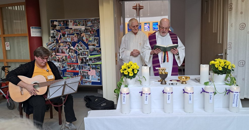 Eine Frau spielt Gitarre und zwei Männer stehen am Altar. 