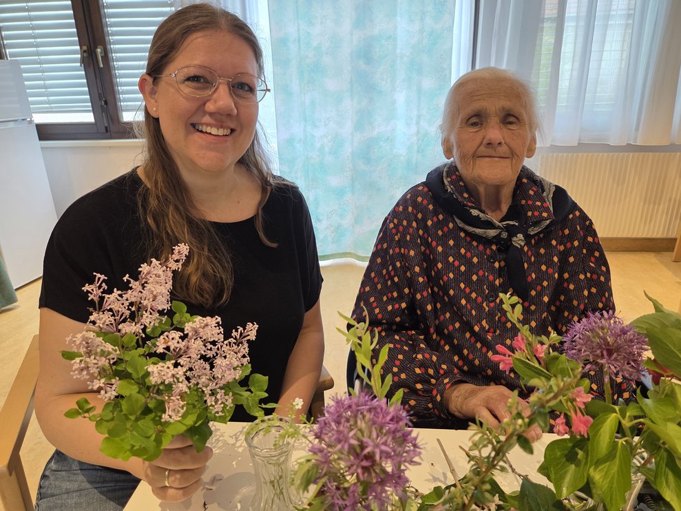 Zwei Damen beim Blumenvasen stecken. 