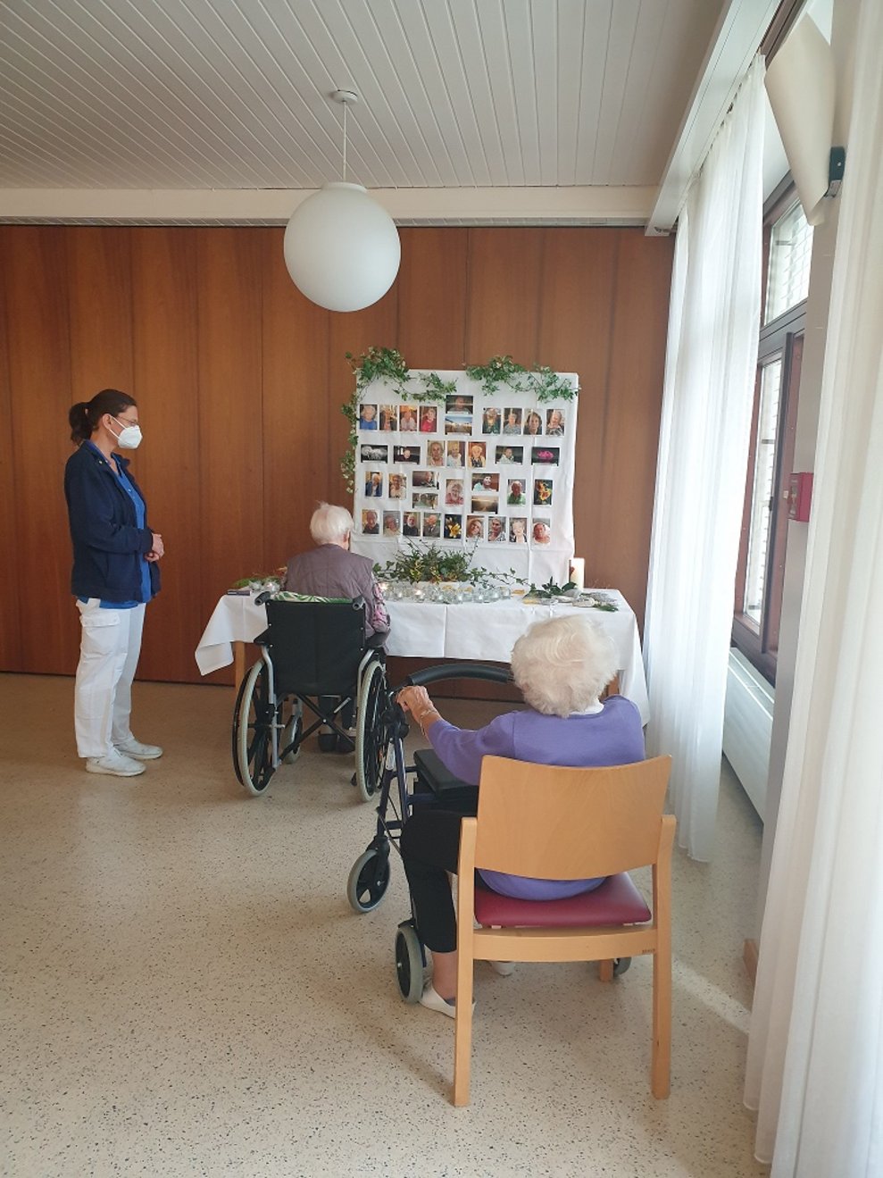 BewohnerInnen sitzen vor der Gedenktafel und die Betreuerin steht neben ihnen.