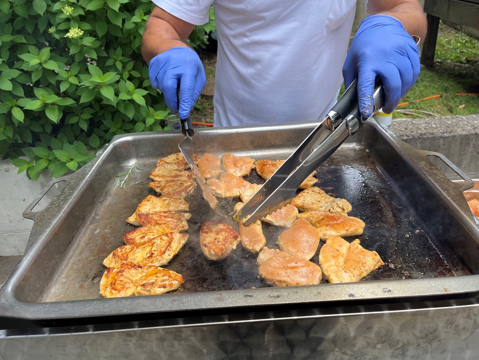 Die Grillplatte mit Hühnerstückchen, die gerade gedreht werden.
