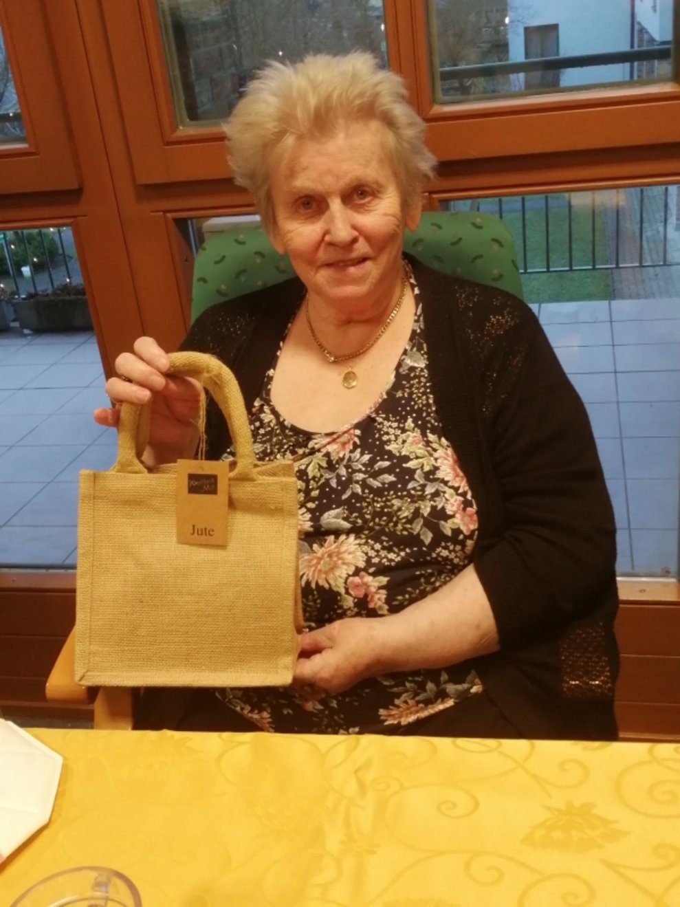 Eine Bewohnerin hält eine Geschenktasche.