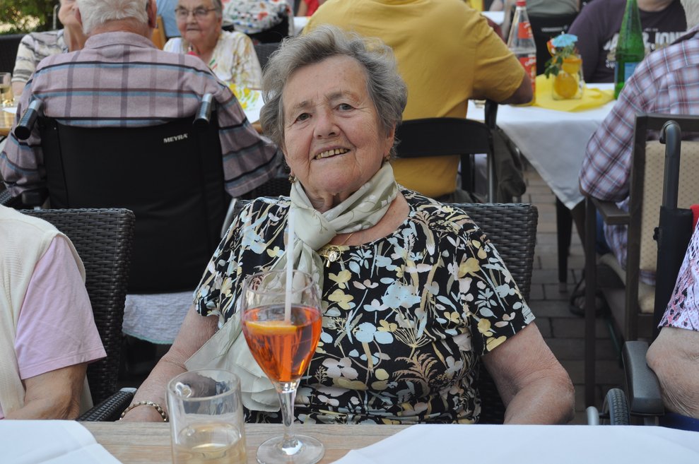eine ältere Frau mit einem Aperol Spritzer