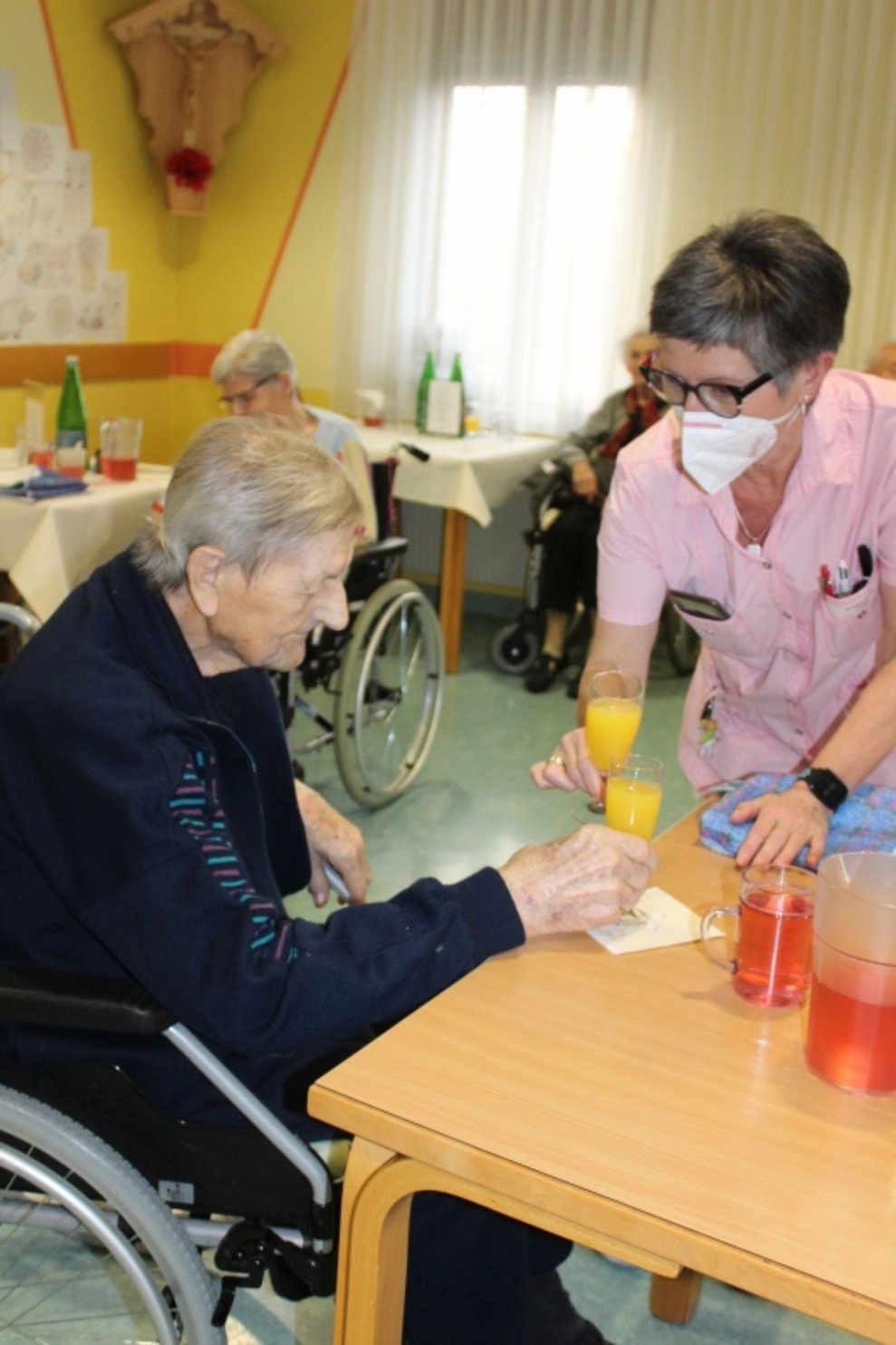 Eine Bewohnerin und eine Betreuerin stoßen an.