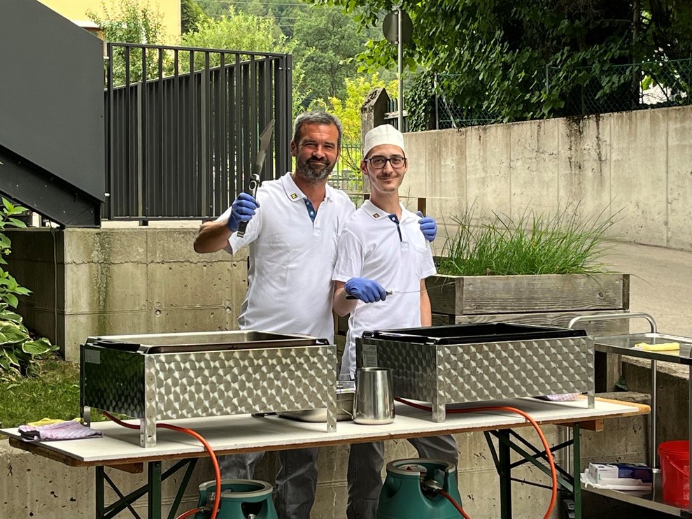Unsere Köche stehen beim Grill und lachen in die Kamera.