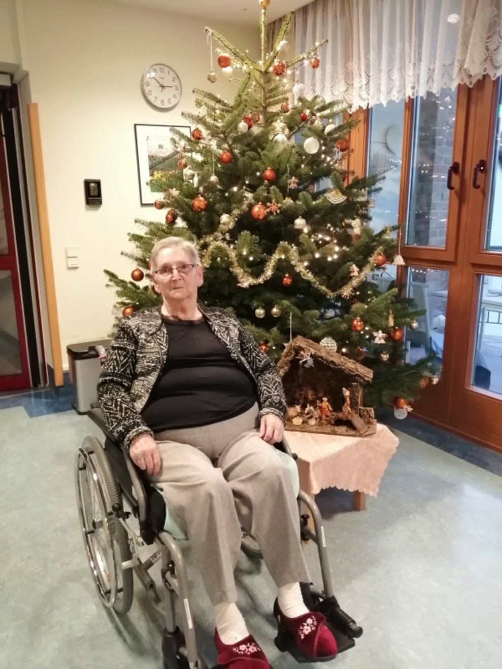 Eine Bewohnerin sitzt beim Christbaum.