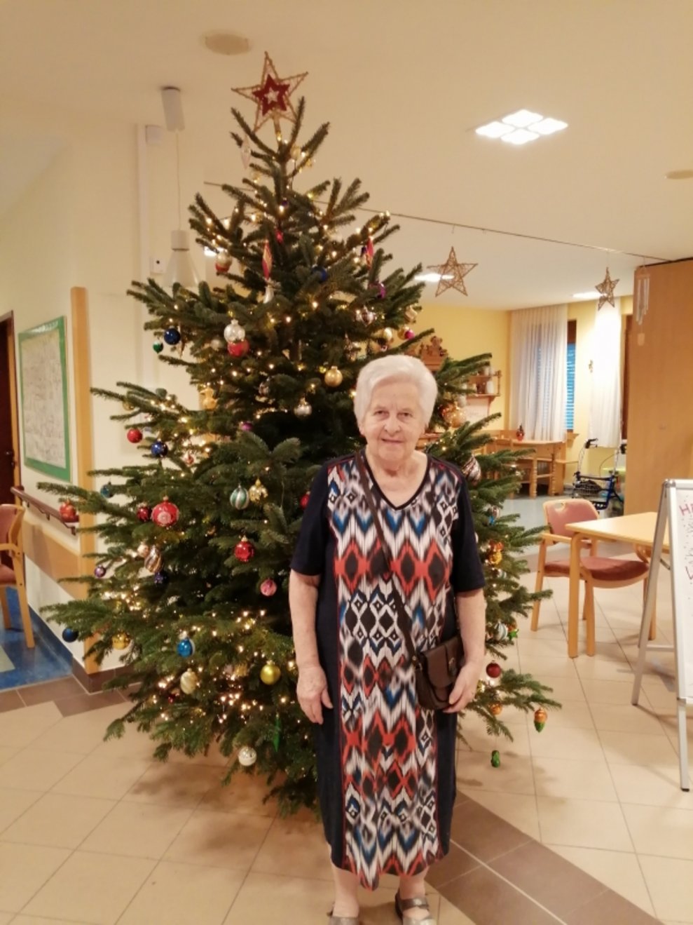 Eine Bewohnerin steht beim Christbaum.