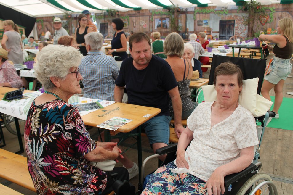 Dame im Rollstuhl vor Tisch mit Begleitperson