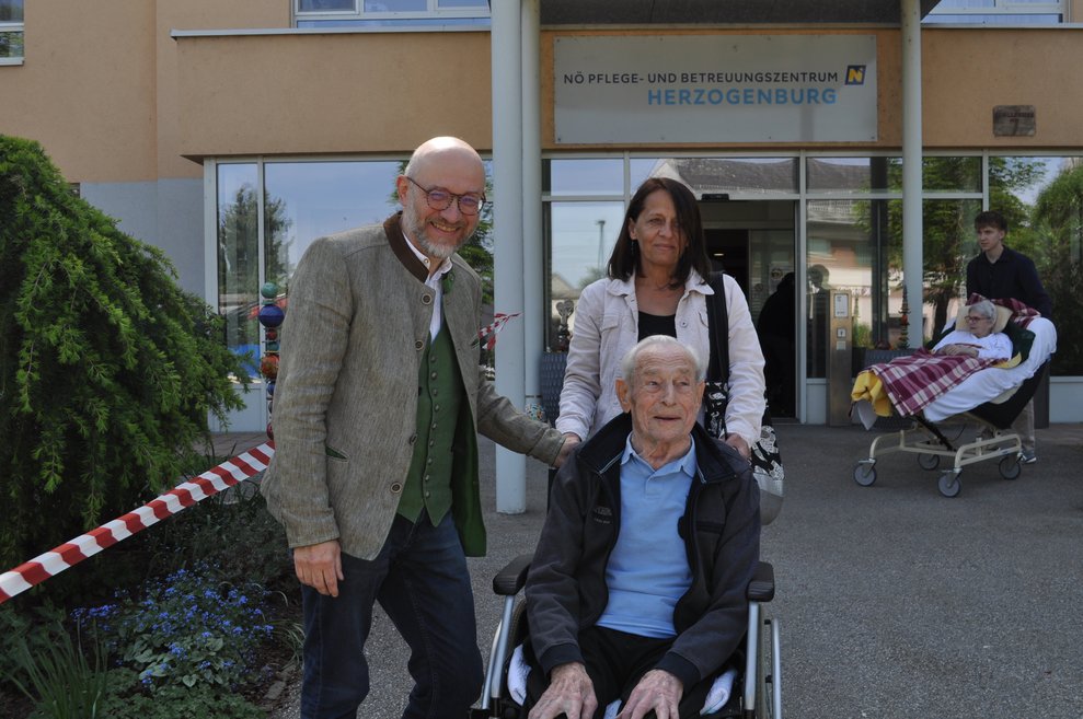 Ein Mann und eine Frau mit einem älteren Herrn im Rollstuhl
