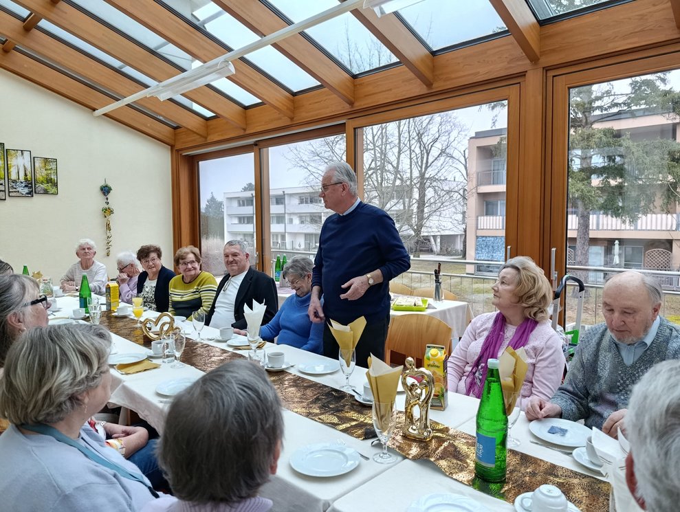 Mann steht. Viele Personen sitzen.