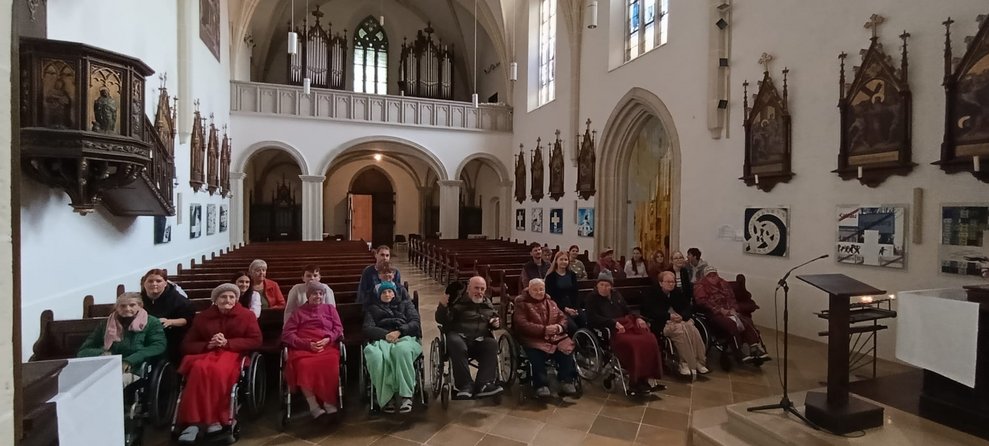Gruppenfoto in der Kirche. (Lehrer, SchülerInnen, BewohnerInnen im Rollstuhl, Alltagsbegleiter, ehrenamtlich Tätige)