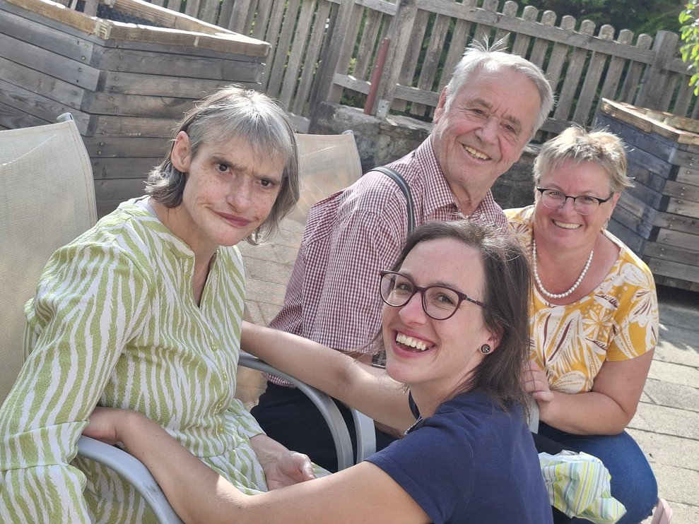 Drei Damen und ein Herr sitzen nebeneinander 