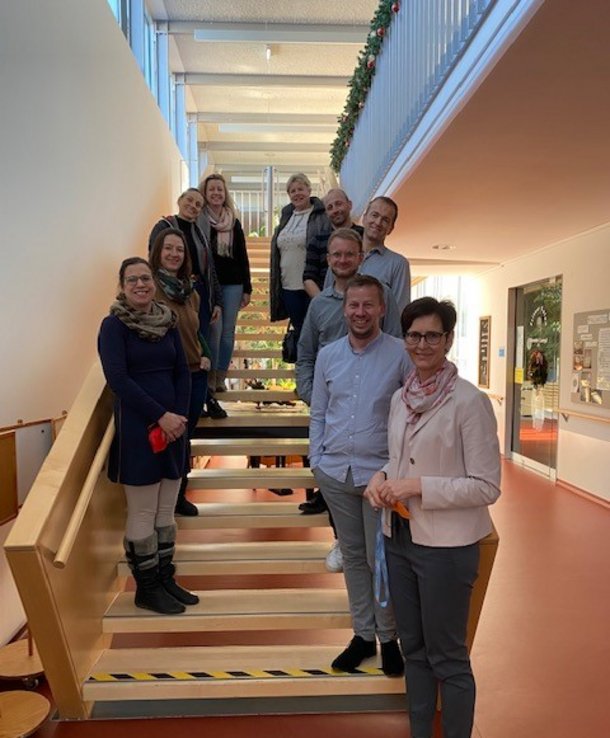 Einige Damen und Herren stehen auf eine Treppe.