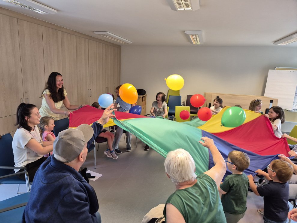 Einige Personen schwingen den "Fallschirm", darauf sind Luftballon.