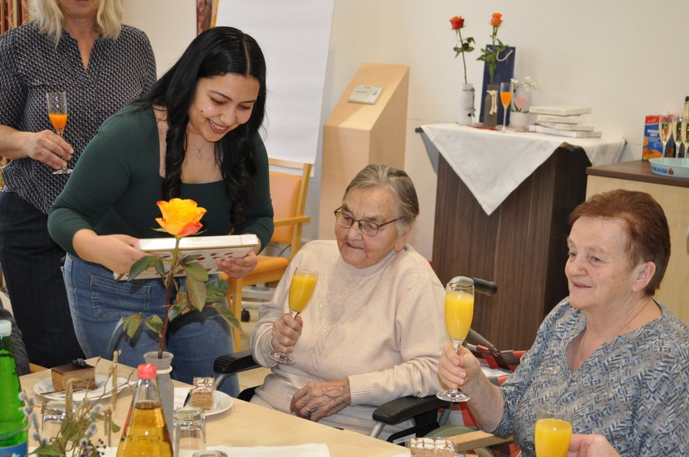 eine Dame gratuliert einer älteren Frau zum Geburtstag