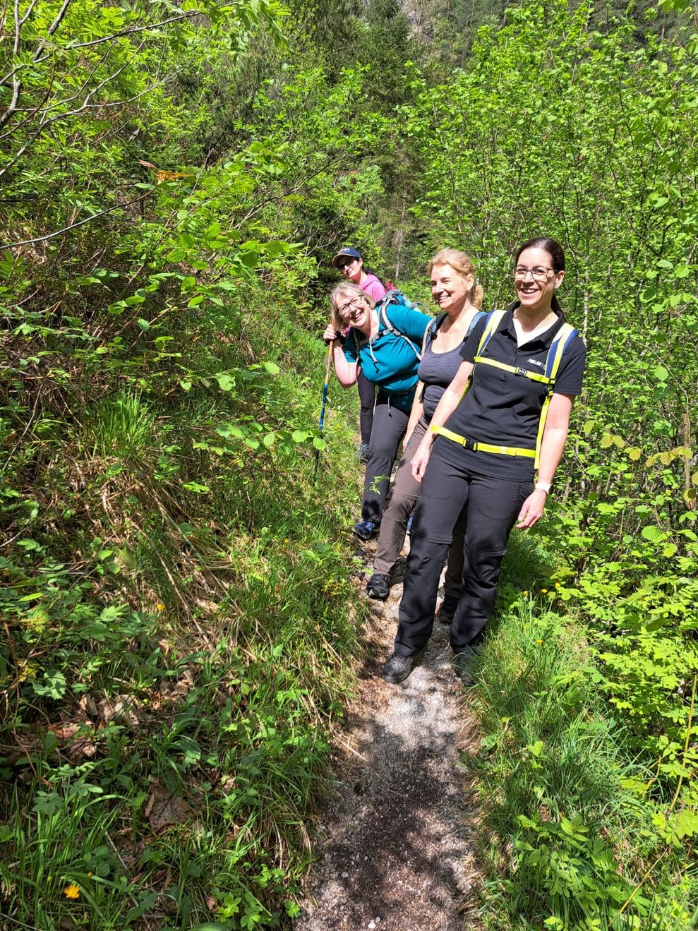 3 Personen gehen hintereinander einen schmalen Weg entlang.