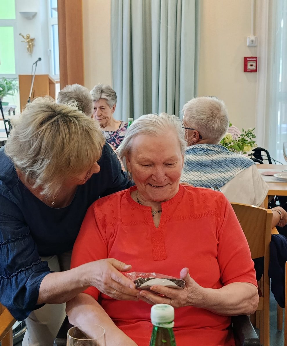 Pflegedirektorin gibt Bewohnerin Schokomuttertagsherz.