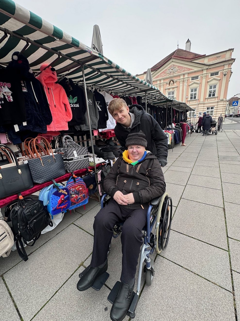 eine Dame im Rollstuhl mit einer Begleitperson am Markt