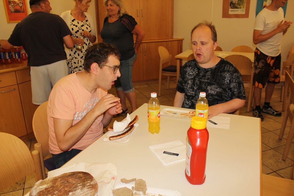 Zwei Herren sitzen bei Tisch und essen.