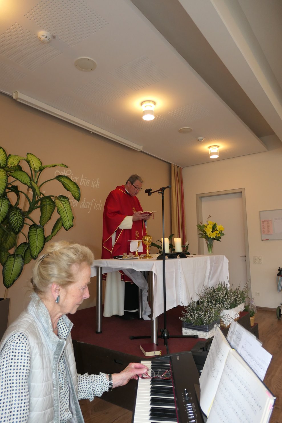 Eine Dame am Klavier und Herr Pfarrer am Altar.