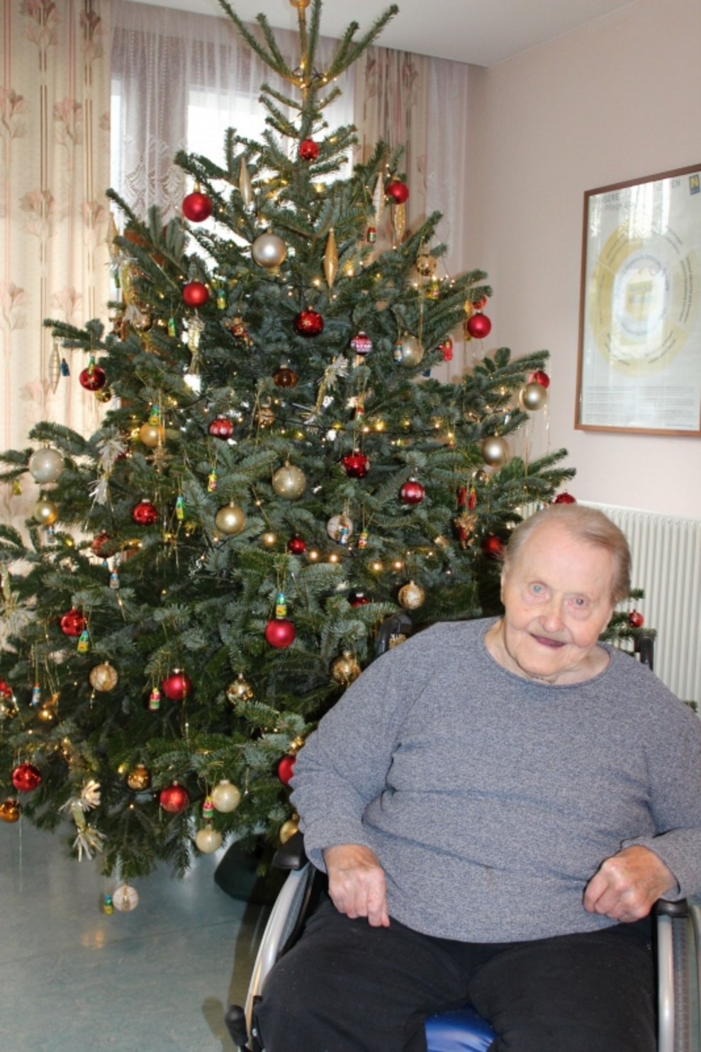 Eine Bewohnerin steht beim Christbaum.
