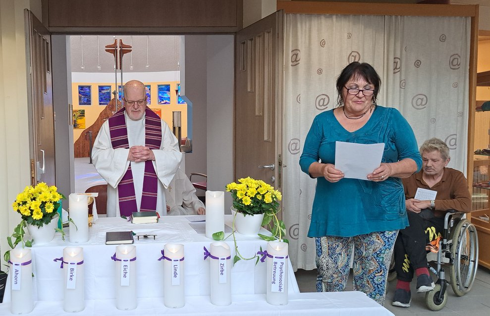 Herr Pfarrer, eine ehrenamtliche Mitarbeiterin und ein Bewohner beim Altar. 