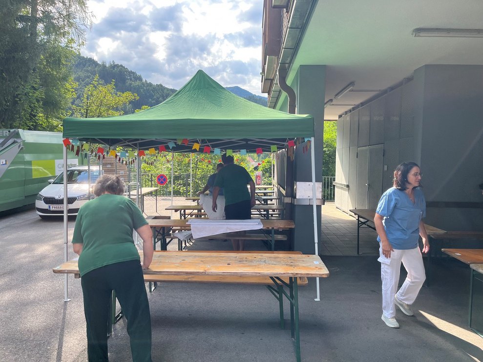 Bewohnerinnen und Bewohner und Mitarbeiterinnen stellen die Tische und Zelte für das Fest auf.