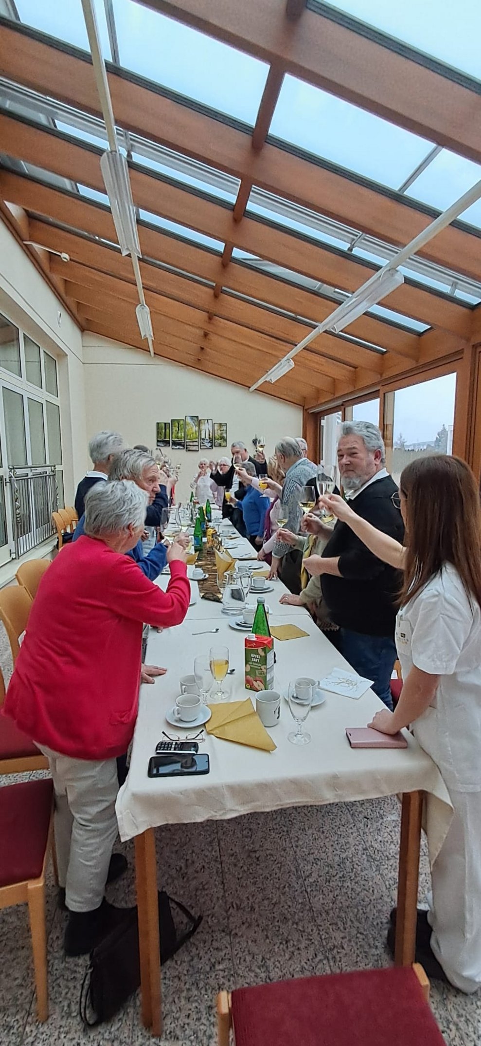 Personen prosten sich stehend mit einem Glas mit Sekt gefüllt zu.