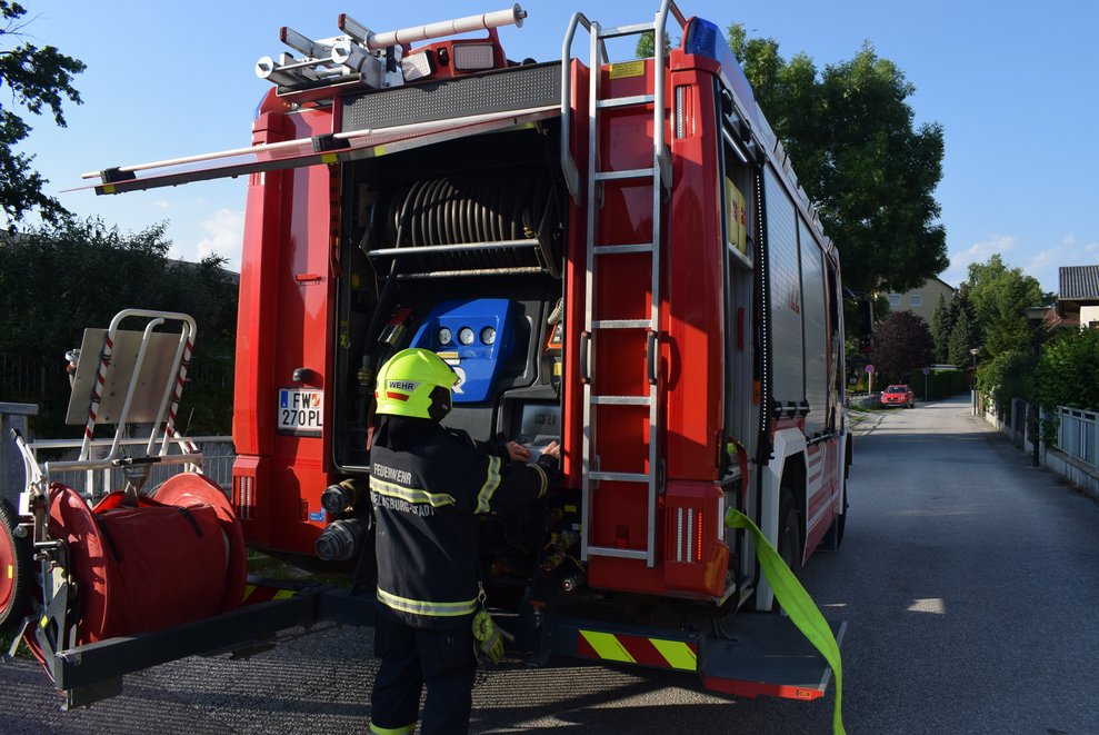 Ein Feuerwehrmann am Heck seines Feuerwehrautos.