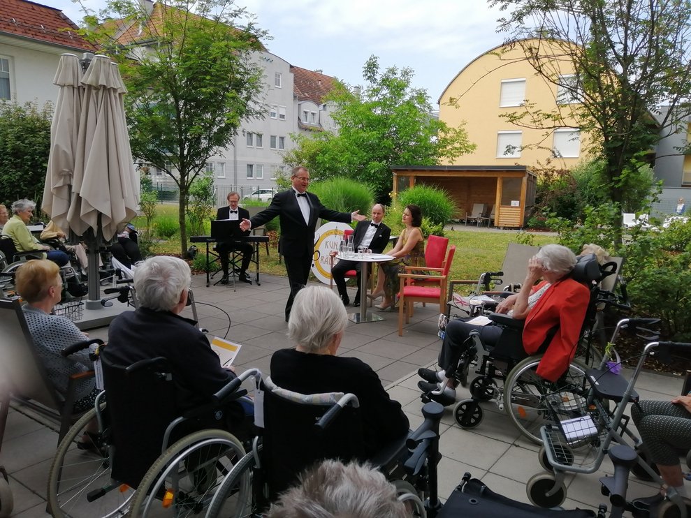 Bewohnerinnen sitzen draußen.