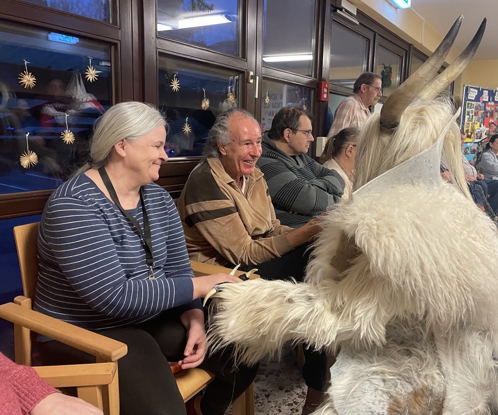 Eine Dame und mehrere Herren begrüßen den Krampus. 