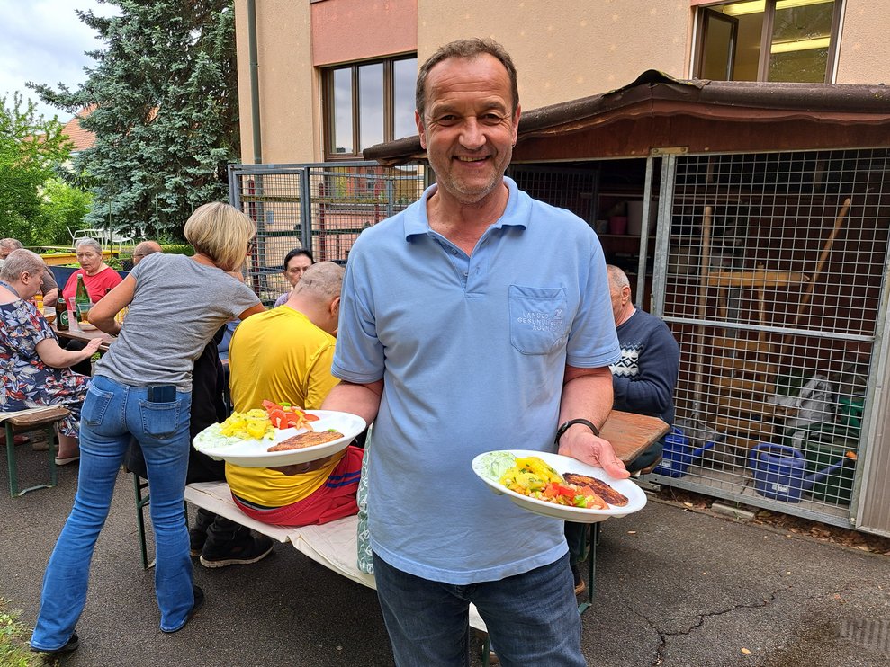 Ein Mann präsentiert die Grillteller.
