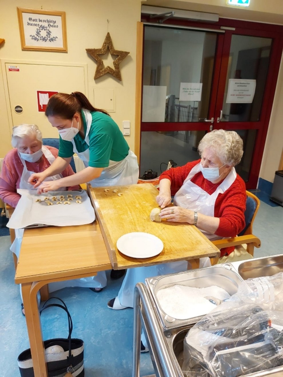 Bewohnerinnen und eine Betreuerin backen Kekse.