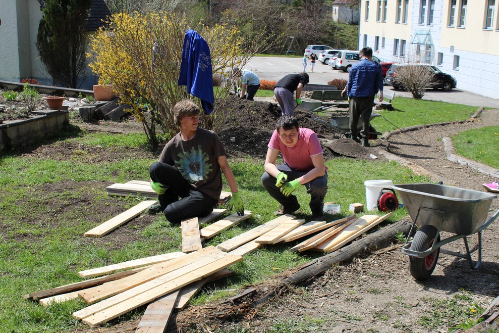 Personen stehen bei Holzpaletten.