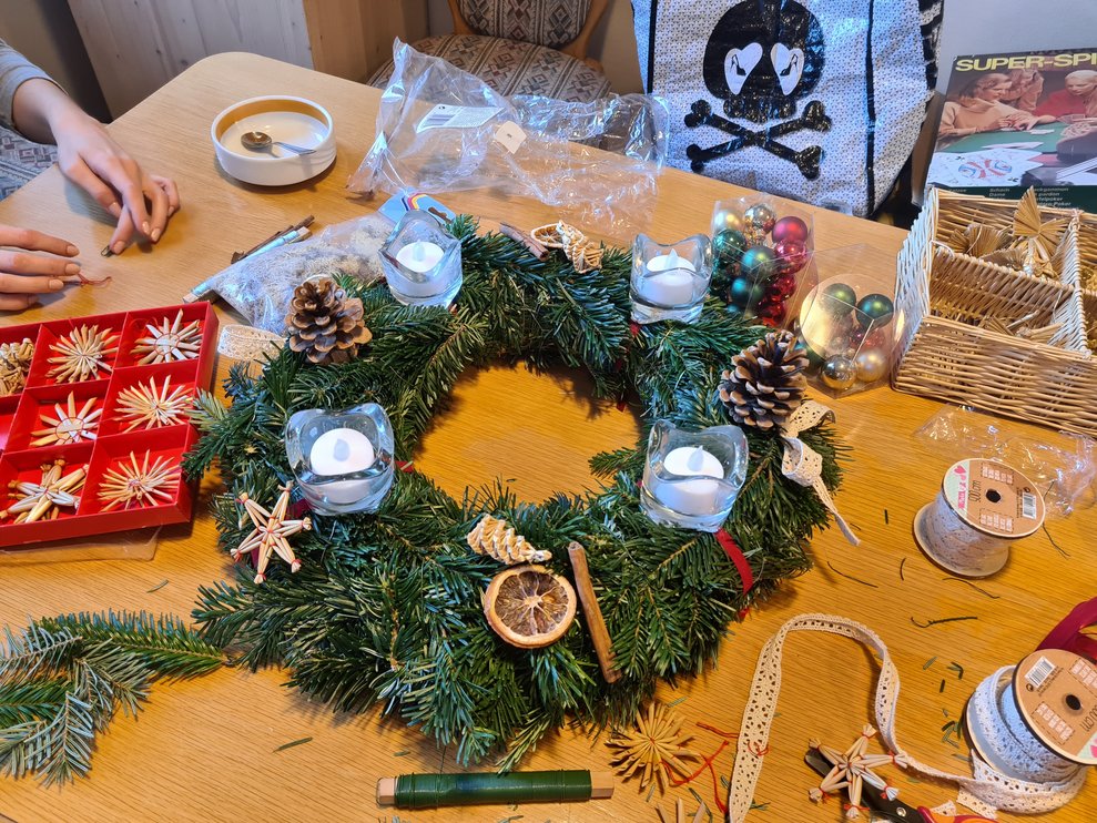 Der Adventkranz wird mit Strohsternen und getrockneten Orangen und Zimt bestückt.