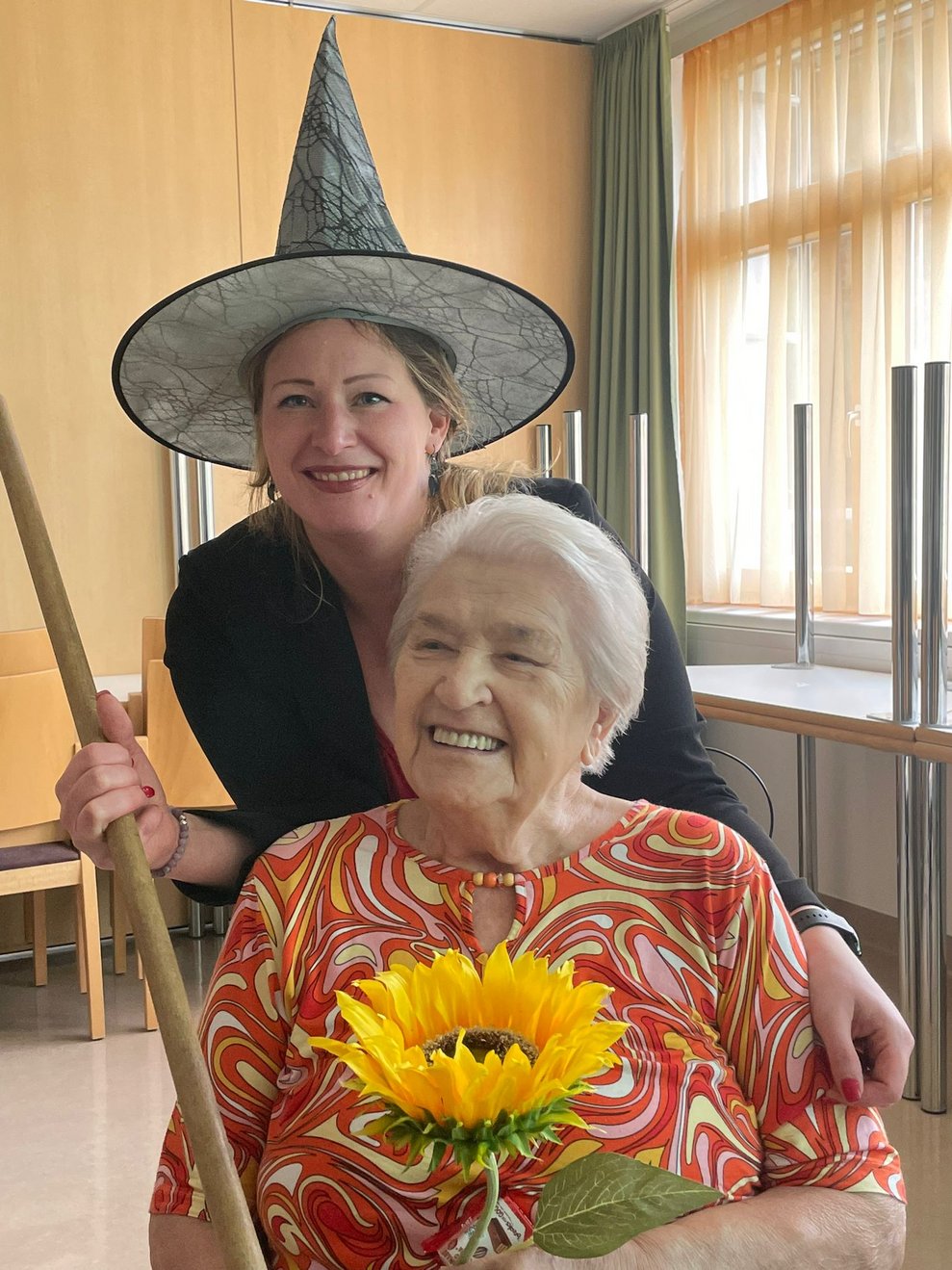 Bewohnerin lächelt mit Hexe und Sonnenblume