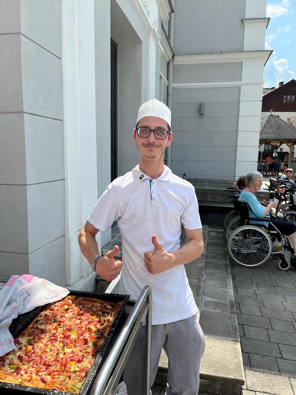 Ein Mitarbeiter aus der Küche bringt selbstgebackene Pizza.