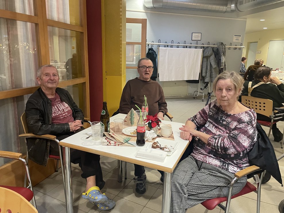Eine Dame und zwei Herren sitzen am Tisch. 