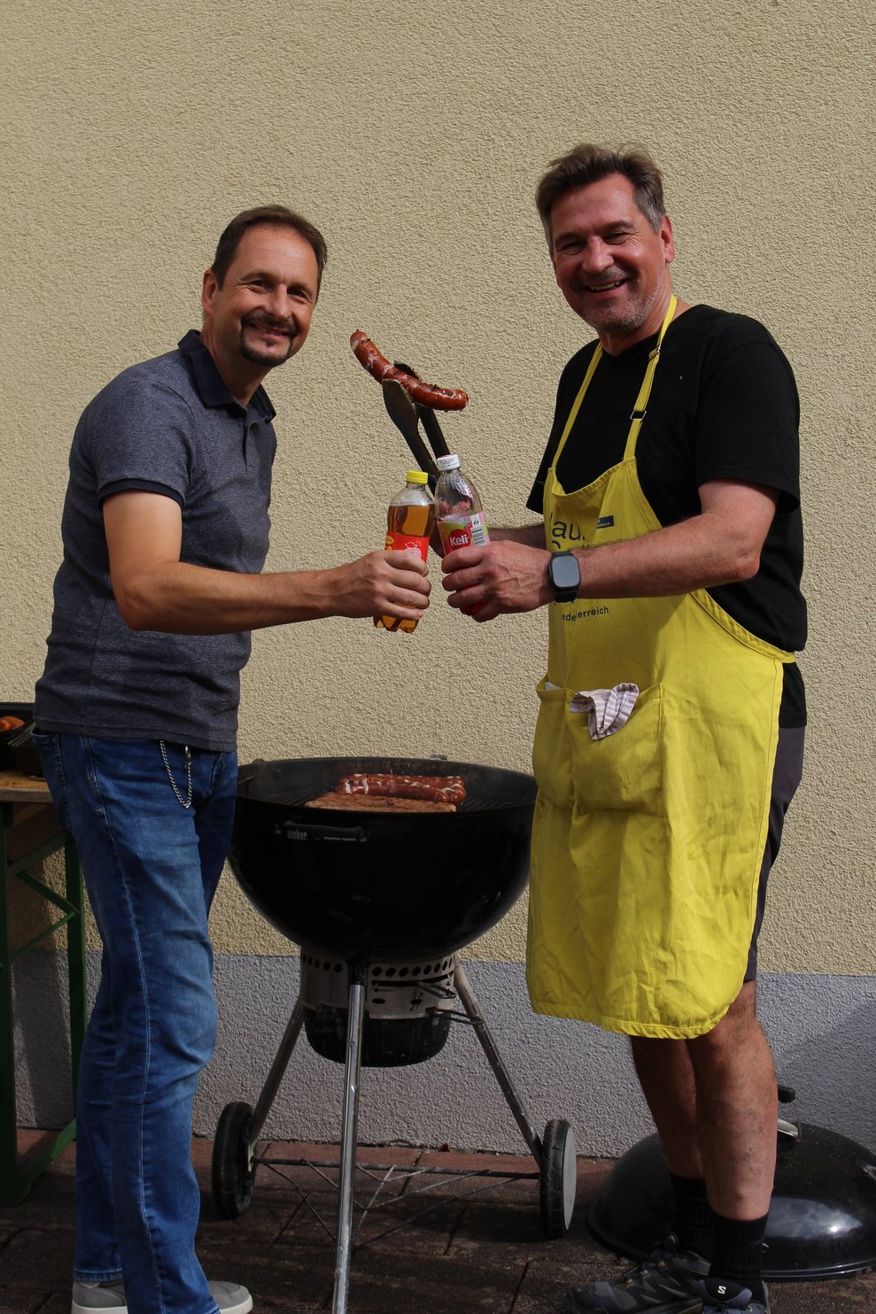 Zwei Männer stehen bei einem Griller