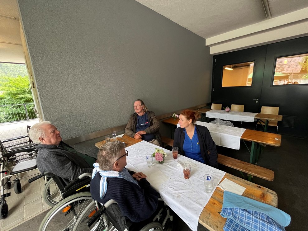 Mitarbeiterin und Bewohner sitzen zusammen und reden.