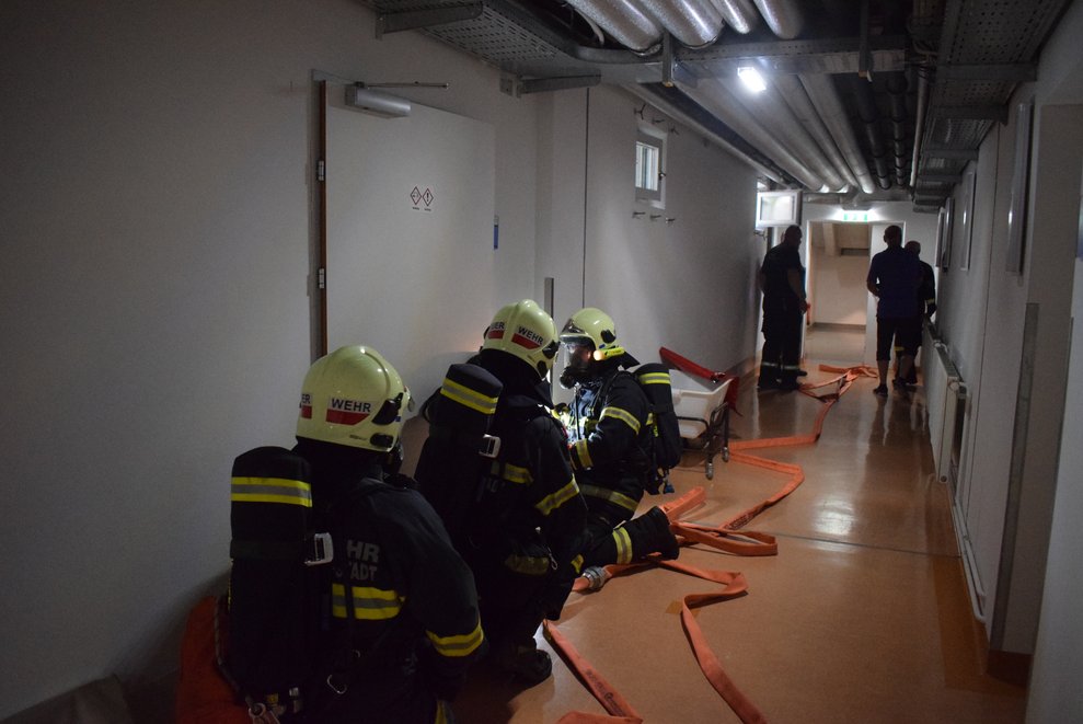 Einige Feuerwehrleute mit Schläuchen im Keller.