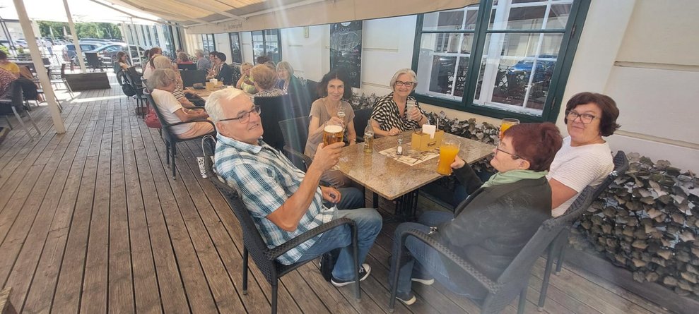 Damen und ein Herr sitzen auf Terrasse