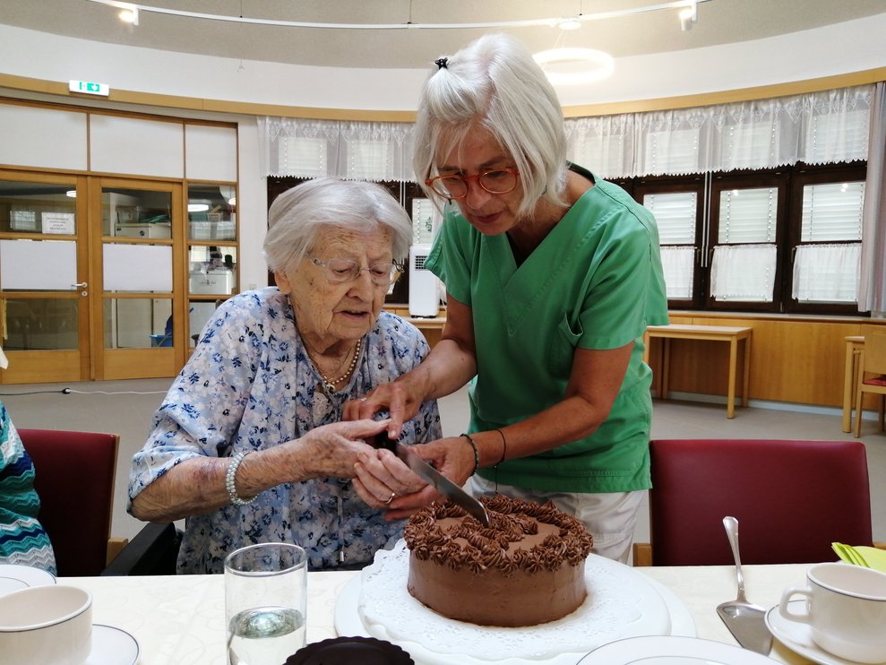 Zwei Damen schneiden die Torte an. 