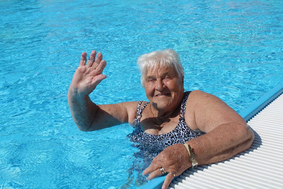 Seniorin im Pool winkt