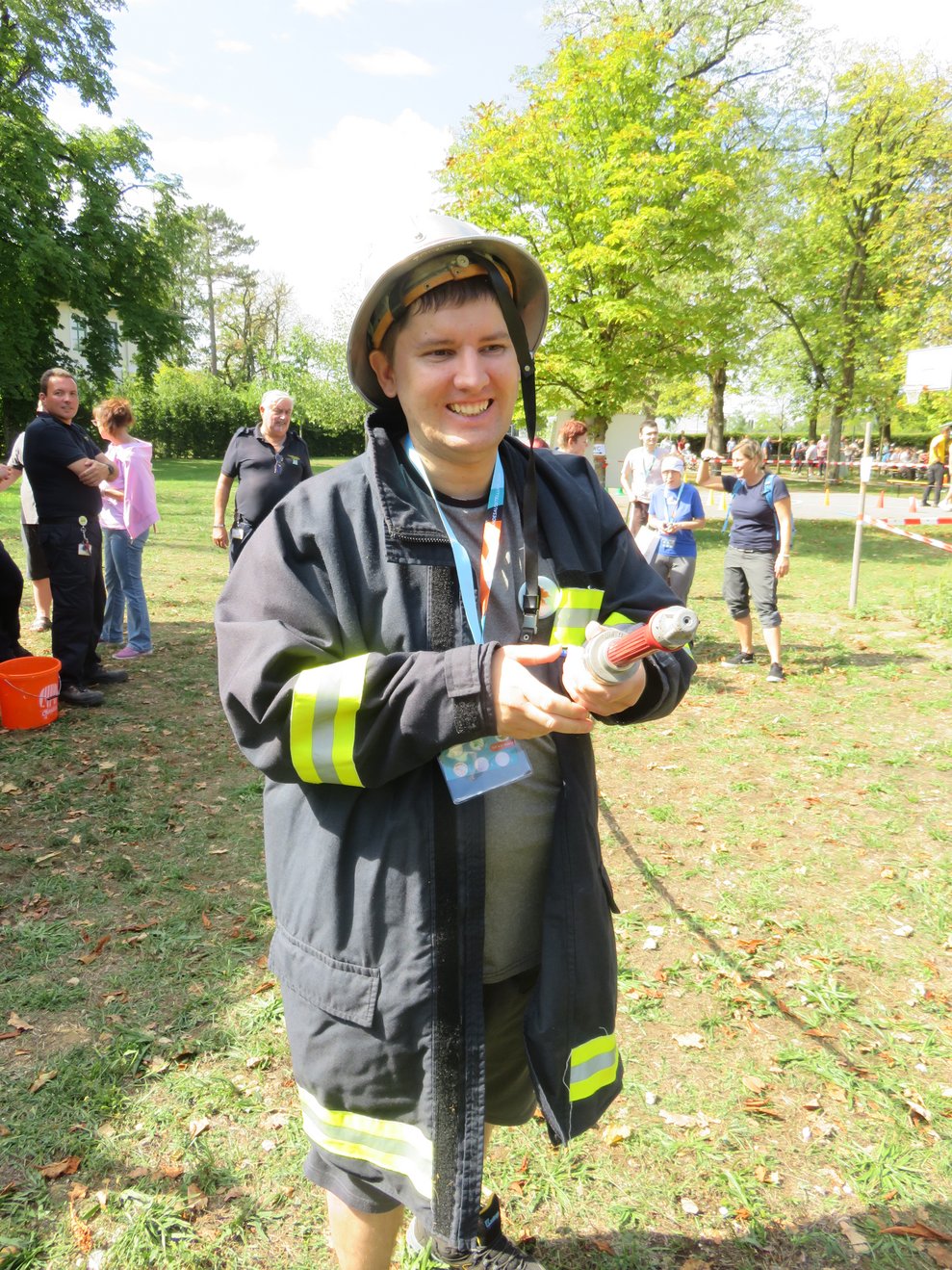Ein Mann hat Feuerwehrgewand an und einen Schlauch in der Hand.