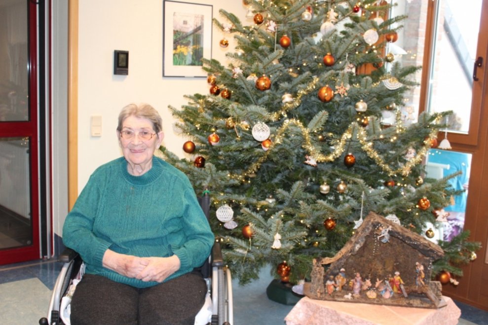 Eine Bewohnerin sitzt beim Christbaum.