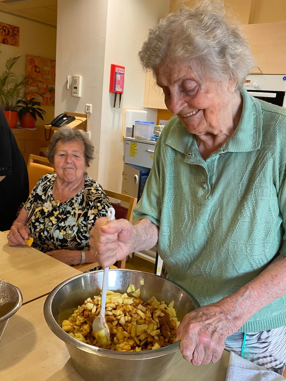 eine ältere Dame beim Rühren der Masse für einen Apfelstrudel